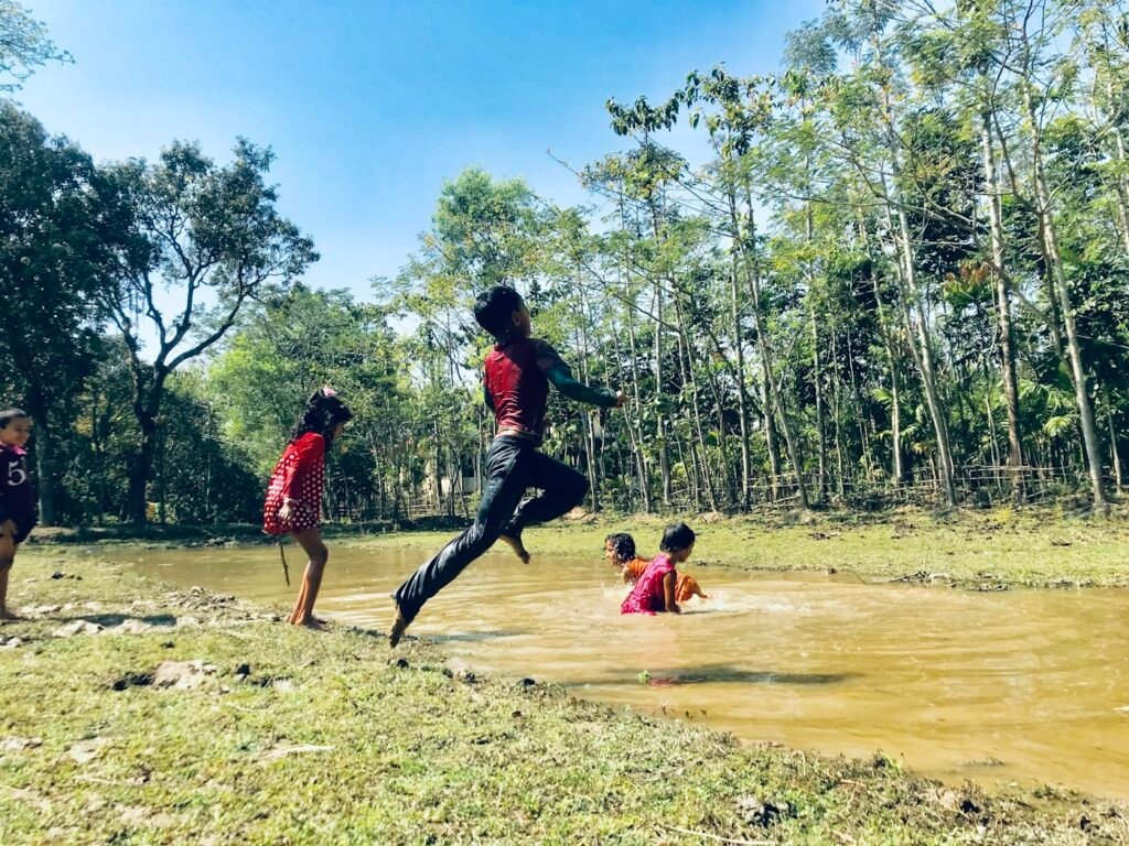 Children playing near a restored wetland area flourishing with native plants.