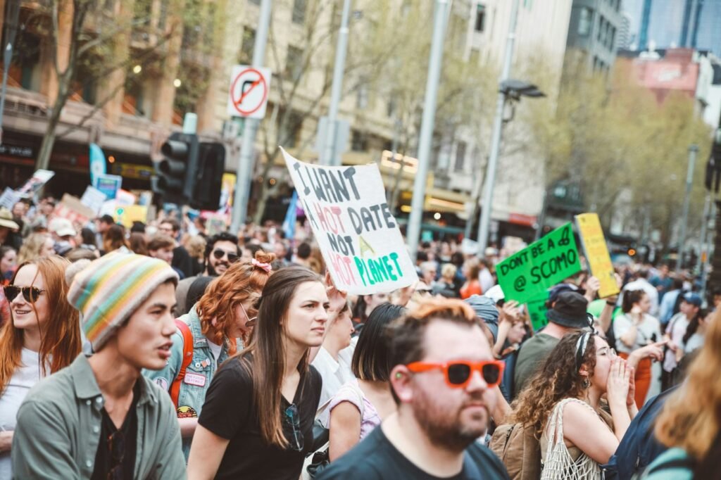 A group of diverse activists gathered in a sunny outdoor meeting, discussing climate plans with maps and laptops.